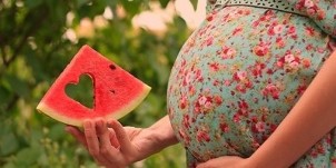 vesimeloni siivu raskaana olevan naisen kädessä